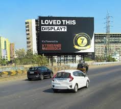 Large outdoor billboard advertising service on busy Indian highway
