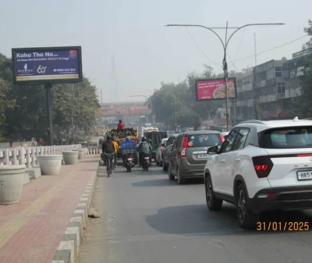 City street with traffic congestion featuring two roadside billboards—one for Bhumika Realty and another for Zomato captured near a pedestrian walkway.