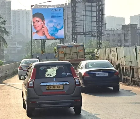Pond’s hydration cream billboard featuring a woman applying cream, located on a flyover with dense vehicle traffic and tall buildings in the background.