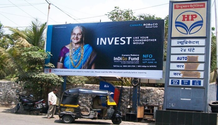 Petrol pump advertising for Canara Robeco Indigo Fund featuring elderly woman visual and NFO promo targeting fuel station visitors.