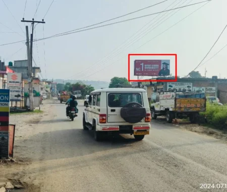Semi-urban street in Himachal Pradesh with 20x10 ft Mandsaur University hoarding by ACME Advertising Co., featuring student visual and education ad; visible white SUV, motorcycle, and roadside service signs.