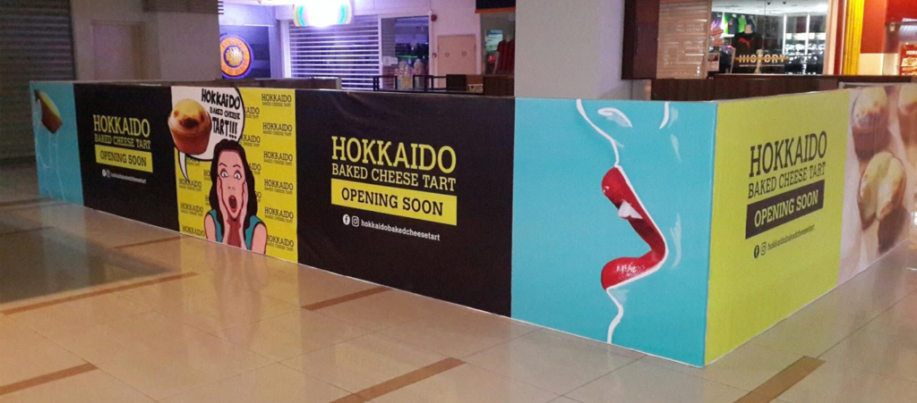 Retail barricade branding with printed panels promoting a food outlet opening soon inside a shopping mall